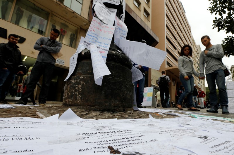 Pessoas olham lista de vagas de emprego em rua no centro de São Paulo
